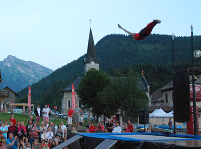 <Acrobatics in St Jean de Sixt>“>The local villages do their best to lure people away from the beaches and into the mountains by offering all sorts of entertainment and activities — many of which are free. For instance, this week is the <em>Aravis et Compagnies</em> family festival. This involves BMX tracks for kids to try out, trampolines, giant plastic balls for kids to get in and float on top of a pool and night-time entertainment, amongst other things. Last night, the acrobats started at 9pm in St Jean de Sixt, with a massive crowd of kids, teens, adults, holiday makers and locals watching. The front of the stage was so packed, you can see people crowding by the side of the stage in this photo (with the l’Etale peak of La Clusaz in the distance). They bounced around, balanced on each others’ heads, and juggled for fifty minutes.</p>
<p>Dusk had turned to night, so the fire dancers started. Not only did they spin giant blazing fans and juggle with fire, they added fireworks to their batons for the last five minutes of the show. What a pity there were a couple of boulders at the front of the stage, blocking the view.</p>
<p>Even though the clock had hit 10.30, the show wasn’t over. A local group (Scummy Band) played some songs that the older kids stayed out to watch, with the band making sure they left out the English swear words from their songs. They played songs from the past five decades and finished after 11pm. Local organisers efficiently packed everything up from the three stages and moved the daytime equipment back into place so the kids would have something to do first thing this morning. And the whole thing was free. We might not have sandy beaches here in the Alps, but the free entertainment during school holidays is fantastic.</p>
<span id=