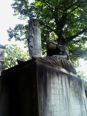 <Photo of a figure on top of a grave at Pere Lachaise cemetery in Paris, France. >